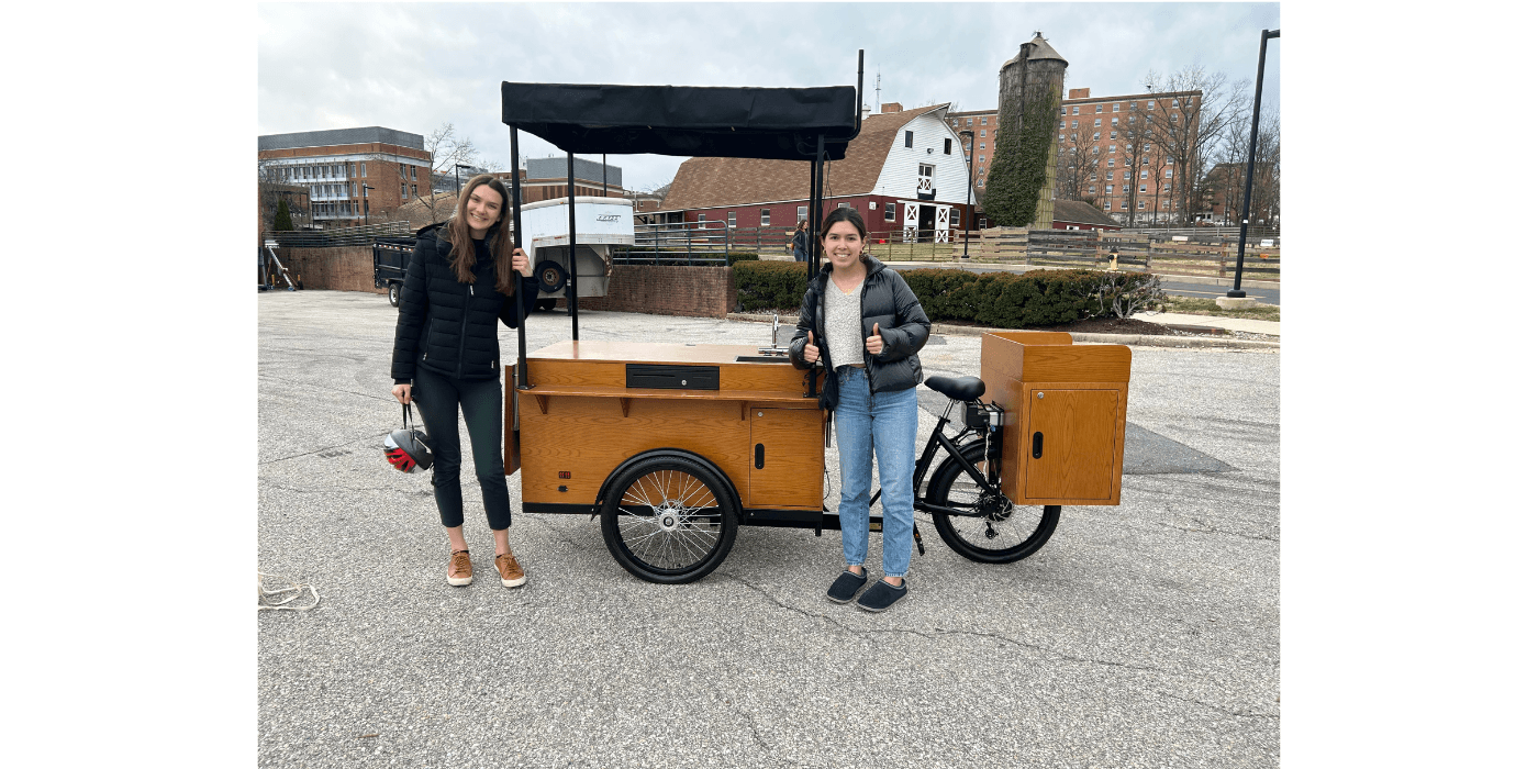 Two people standing in front of a coffee cart
