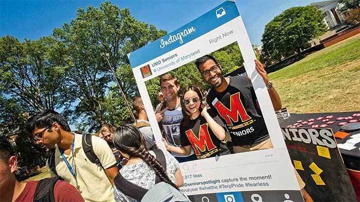 Maryland Day attendees take a selfie with a cardboard cutout of an instragram post